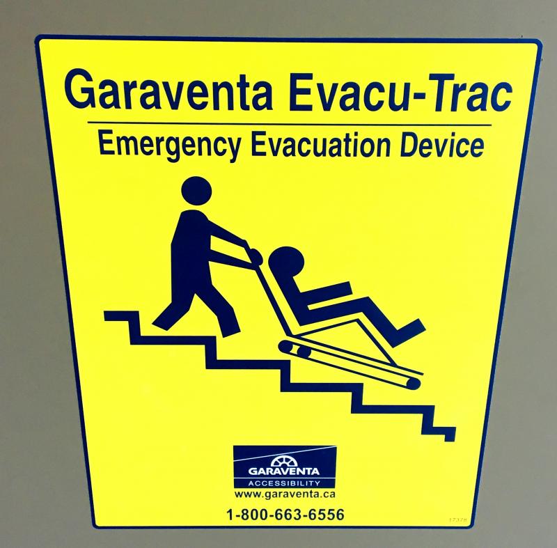 Image of sign for an evacu trac, an emergency carrier for individuals with mobility limitations. All information included in main text.