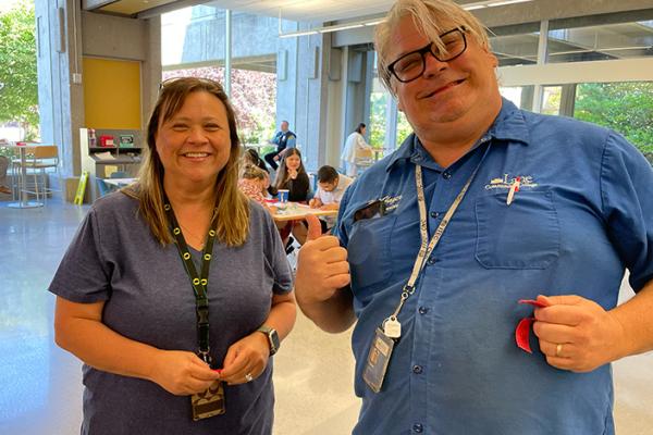two employees, a man and a woman with lanyards, smiling and laughing at classified appreciation day