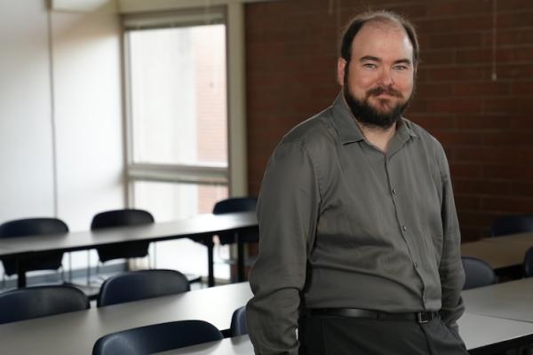 a business instructor smiling as he poses in his classroom