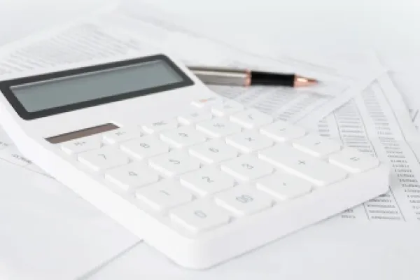 Calculator and pencil sit on some papers.