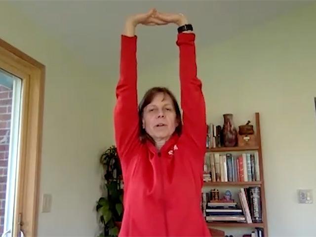 a woman at a desk in her office stretches her arms above her head
