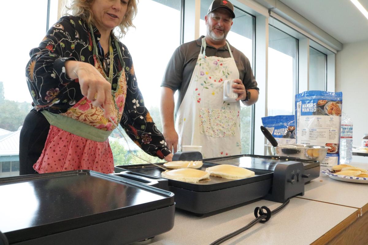 Two colleagues making pancakes together at the CTL community breakfast.