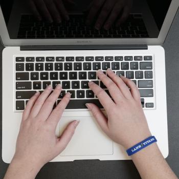 an employee wearing a Lane Titans bracelet using a MacBook Air computer