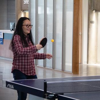 an employee laughs and plays ping pong in the Center Building