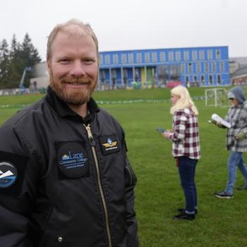 drone instructor Sol Singer smiling and wearing a LCC jacket with his students on a field on campus