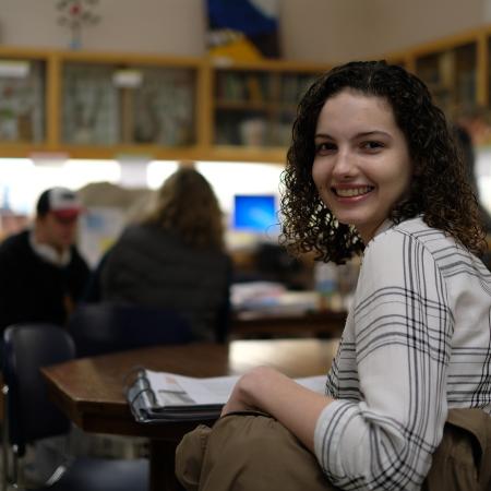 a young woman with curly hair and bright smile in a science classroom