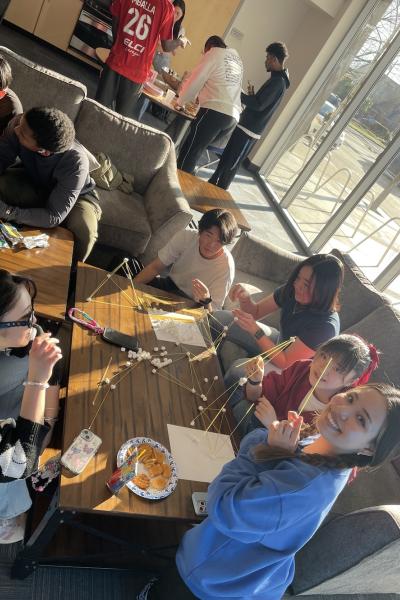international students laugh and work on a craft together at Titan Court
